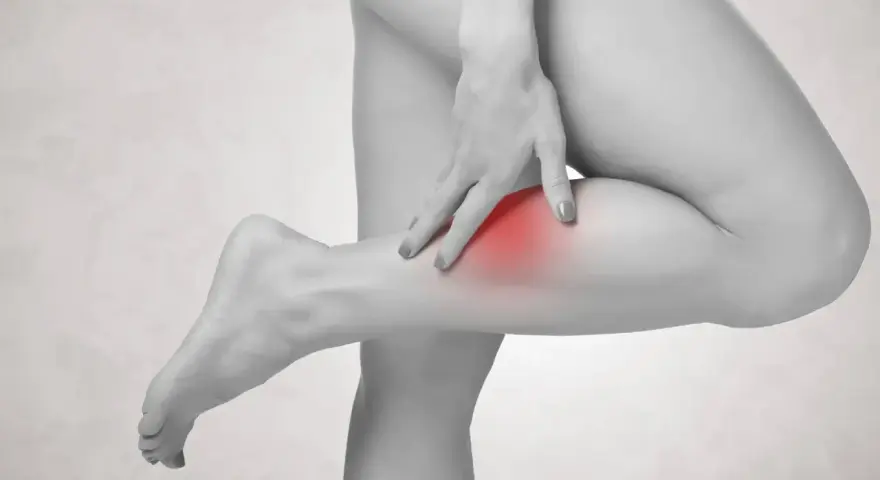 Frau tastet schmerzendes Bein ab, ein roter Fleck deutet auf einen möglichen Thrombose-Test hin.