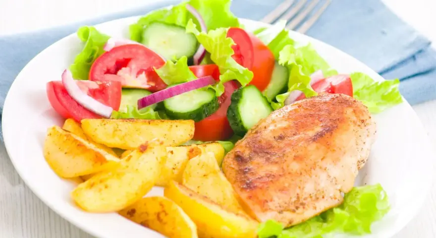 Petto di pollo in friggitrice ad aria, patate arrosto e insalata fresca con pomodori, cetrioli e cipolla rossa.
