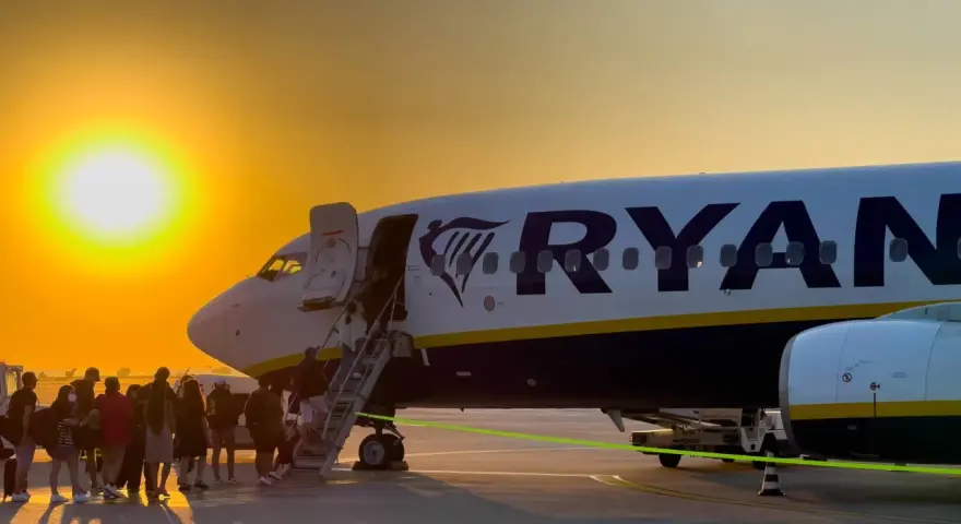 Zachód słońca nad lotniskiem, pasażerowie wsiadają do samolotu Ryanair. Marzysz o tanich podróżach? Ryanair loty za 1 zł to szansa na przygodę!