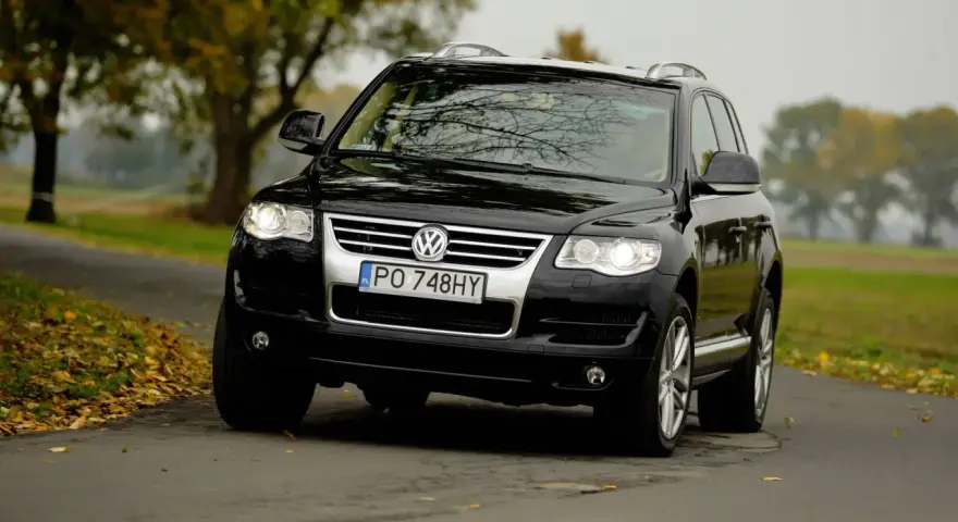 Czarny VW Touareg 2.5 TDI R5 na jesiennej drodze. Choć to solidne auto, warto znać jego potencjalne wady.