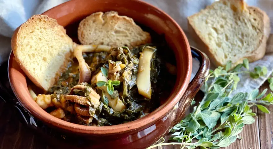 Seppie in zimino, un piatto tradizionale con seppie tenere e verdure, servito in una ciotola di terracotta con pane tostato e erbe aromatiche.