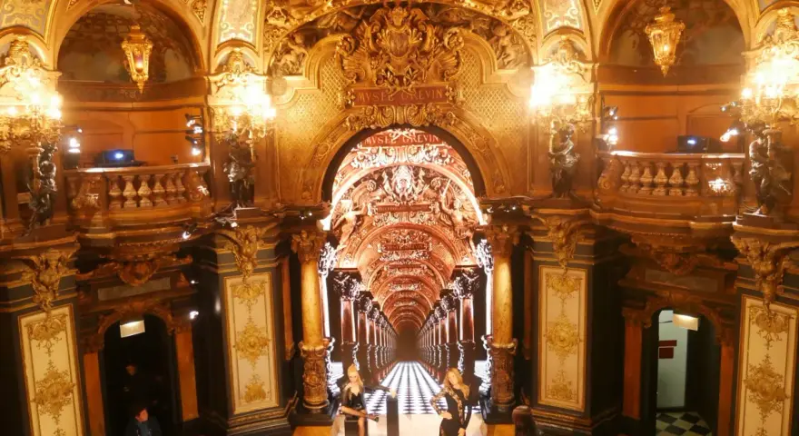 L'intérieur doré et orné du musée Grévin à Paris, avec des statues de cire et un sol à damier.
