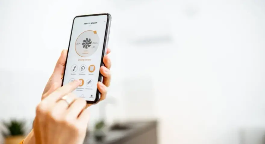 Mano usando un smartphone para encender calefacción a distancia en la sala de estar.