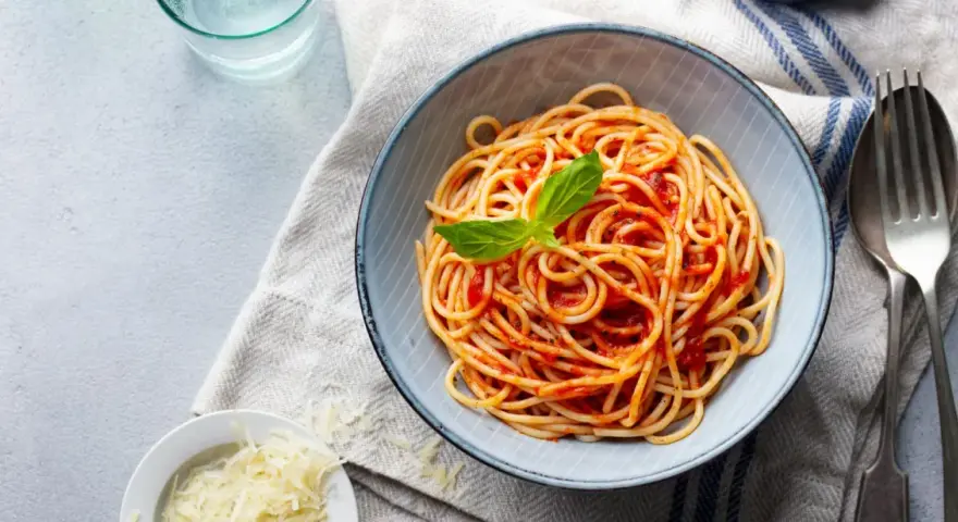 Misternie ułożone spaghetti z sosem pomidorowym i listkiem bazylii. Idealne jakie przyprawy do spaghetti? Sól, pieprz i odrobina czosnku.
