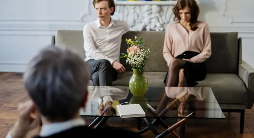 Un couple en discussion avec un avocat, cherchant une aide juridictionnelle pour leur divorce.