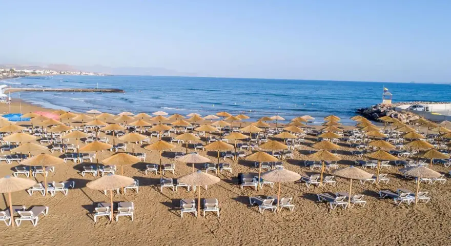Plaża sol marina beach crete z rzędami leżaków i parasoli, gotowa na gości. Błękitne morze i niebo tworzą idealne tło.