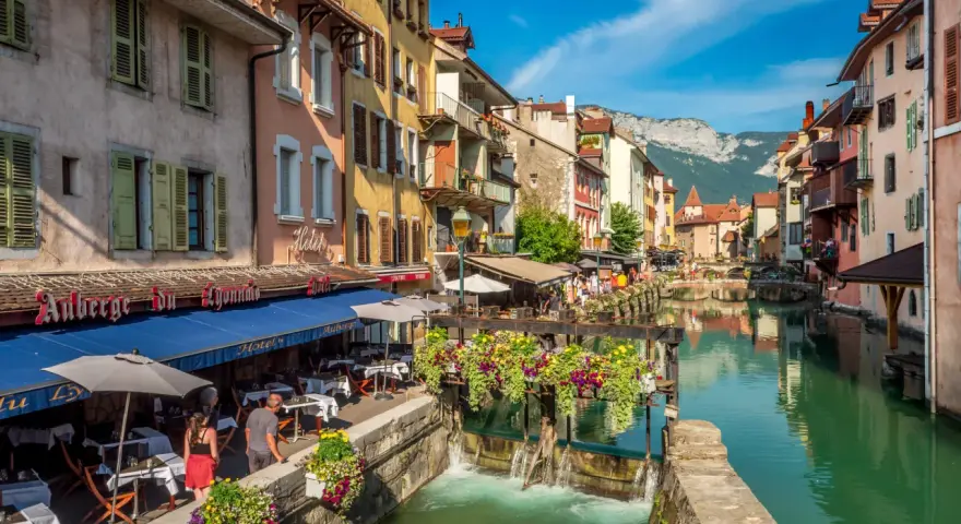 Canal animé à Annecy, avec des restaurants en terrasse et des fleurs colorées. Idéal pour découvrir les choses à faire à Annecy.