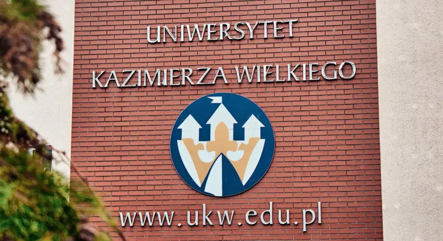 Elewacja Uniwersytetu Kazimierza Wielkiego w Bydgoszczy z logo i adresem strony.