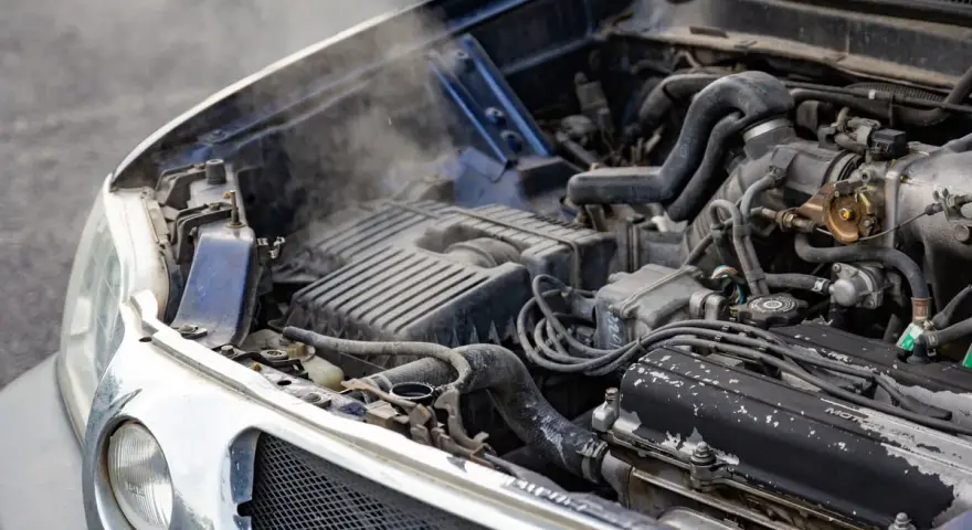 Steam rises from an overheated car radiator, indicating a potential engine problem.