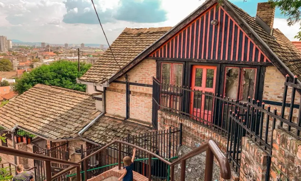 Schody prowadzące do urokliwego domu z różowymi drzwiami. Widok na panoramę miasta, idealne miejsce, by odkryć, co zobaczyć w Belgradzie.