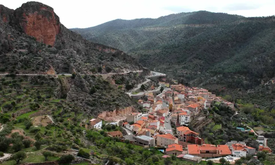 Pueblo encajado en un valle, con casas de tejados naranjas y una carretera serpenteante. Descubre qué ver en Ayna, un rincón pintoresco.