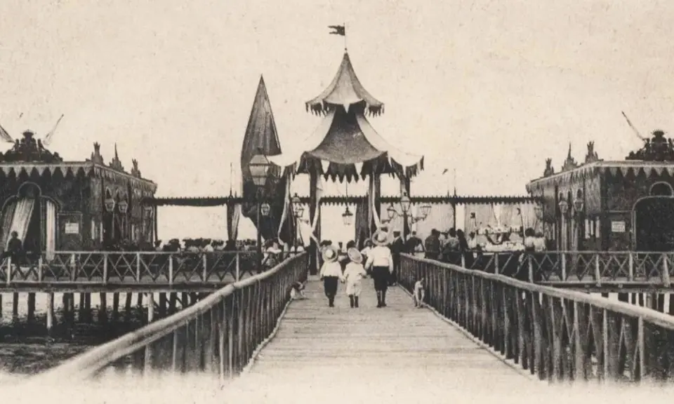 Antica passeggiata sui bagni isola di Cervia, con bambini che camminano sul pontile verso le strutture sul mare.