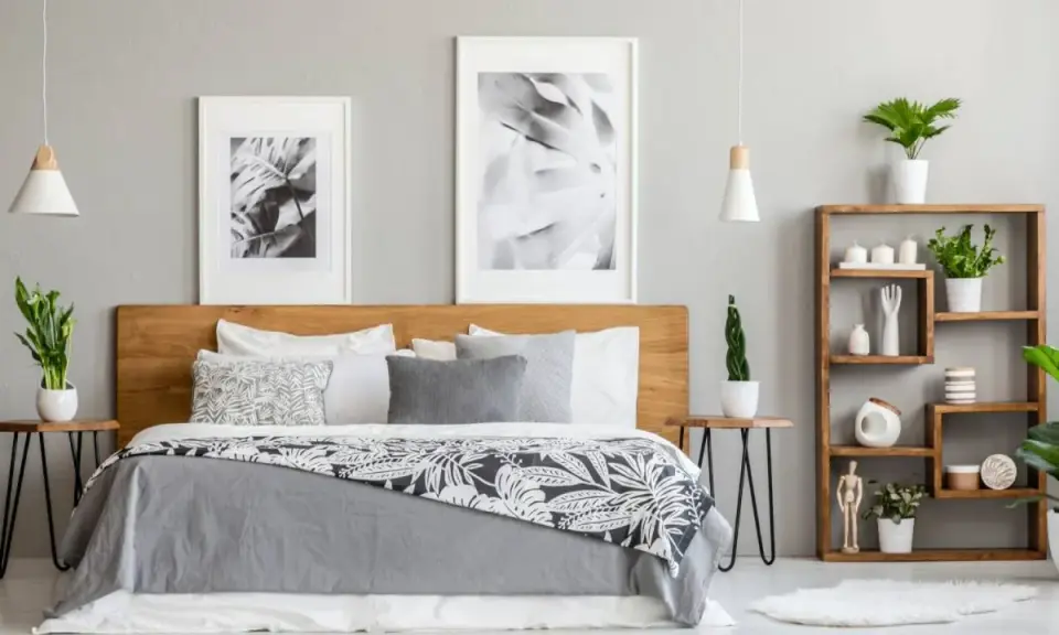 Dormitorio moderno con cama de madera, cuadros botánicos y estantería. Los tonos grises para paredes interiores crean un ambiente sereno y elegante.