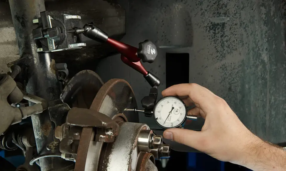 Mechanik mierzy bicie tarczy hamulcowej, by zdiagnozować drgania kierownicy przy hamowaniu.