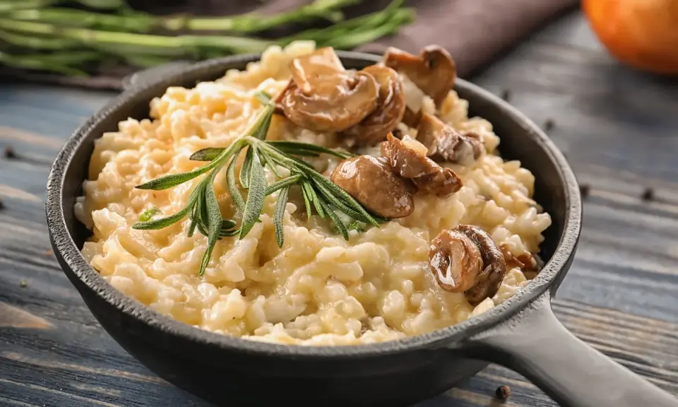 Cremoso arroz redondo risotto con champiñones salteados y romero fresco en sartén de hierro fundido.