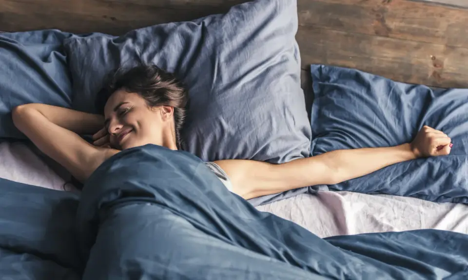 Frau streckt sich im Bett. Wenn man nicht schlafen kann, hilft es manchmal, sich zu bewegen.