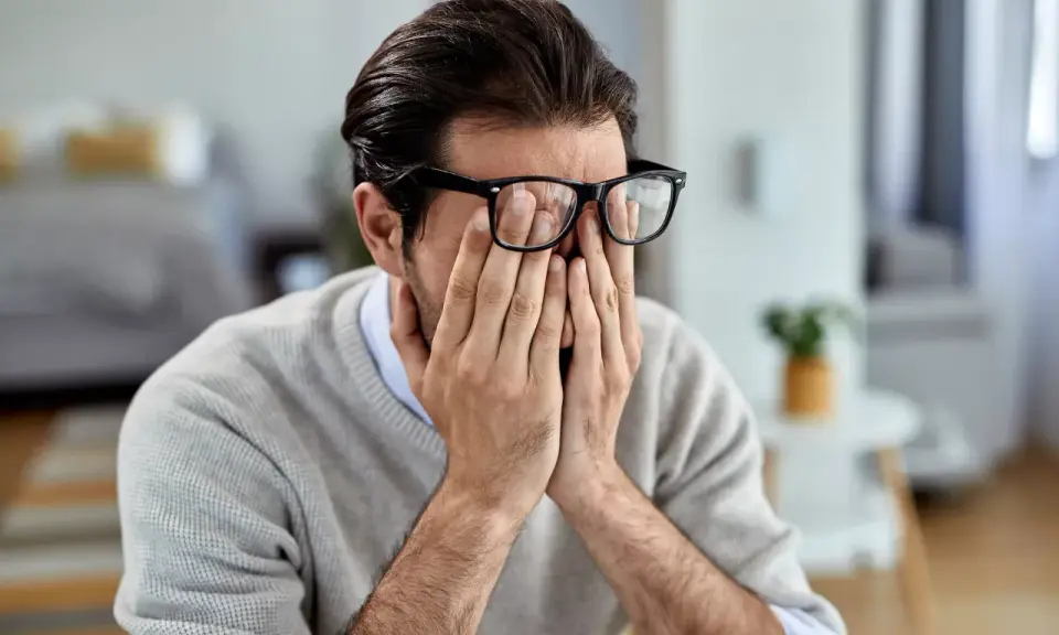 Mann mit Brille reibt sich die Augen, wirkt gestresst. Manche glauben, rauchen hilft gegen Stress, doch das ist ein Trugschluss.