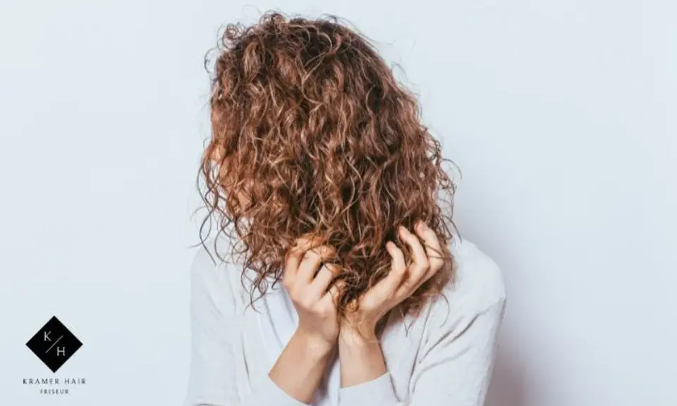Frauen mit einer voluminösen Dauerwelle, die ihre Hände durch die Locken gleiten lassen.