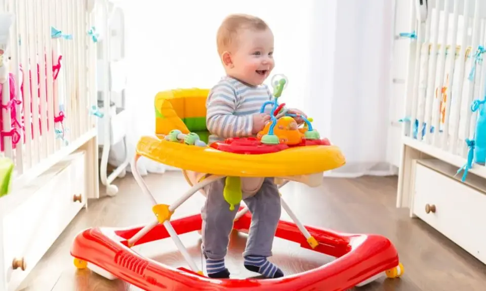 Uśmiechnięty maluch w chodziku bawi się zabawkami. Od kiedy chodzi, świat jest dla niego jeszcze ciekawszy!