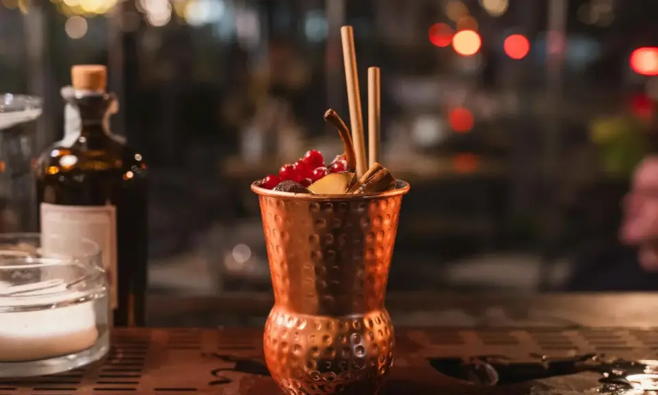 Cocktail in rame, decorato con frutti rossi e cannella, perfetto per un aperitivo Milano Marittima.