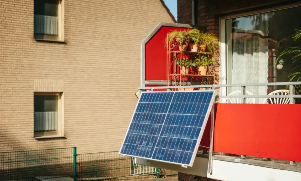 Panneau solaire sur un balcon rouge, peut-être pour contester une augmentation de loyer liée au DPE.