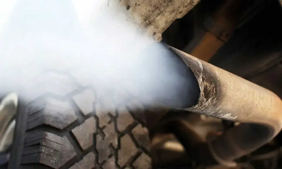 Biały dym z wydechu diesel wydobywa się z rury, zasłaniając fragment opony.