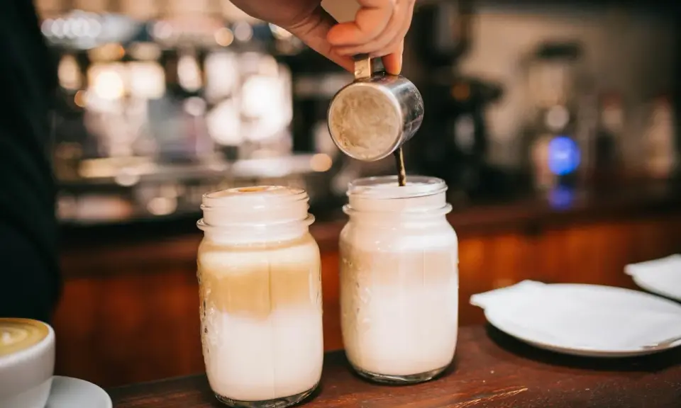 Barista bereitet Latte Macchiato zu. Die Frage "wie viel Kalorien hat ein Latte Macchiato" beschäftigt viele Genießer.