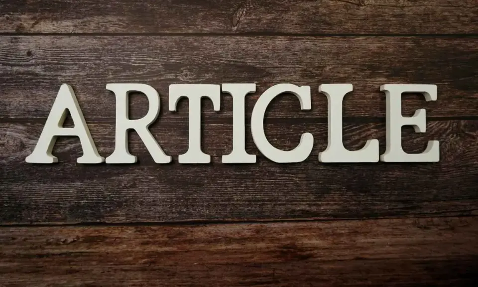 Białe litery układają się w słowo "ARTICLE" na drewnianym tle. To zapowiedź rozszerzonego artykułu po angielsku.