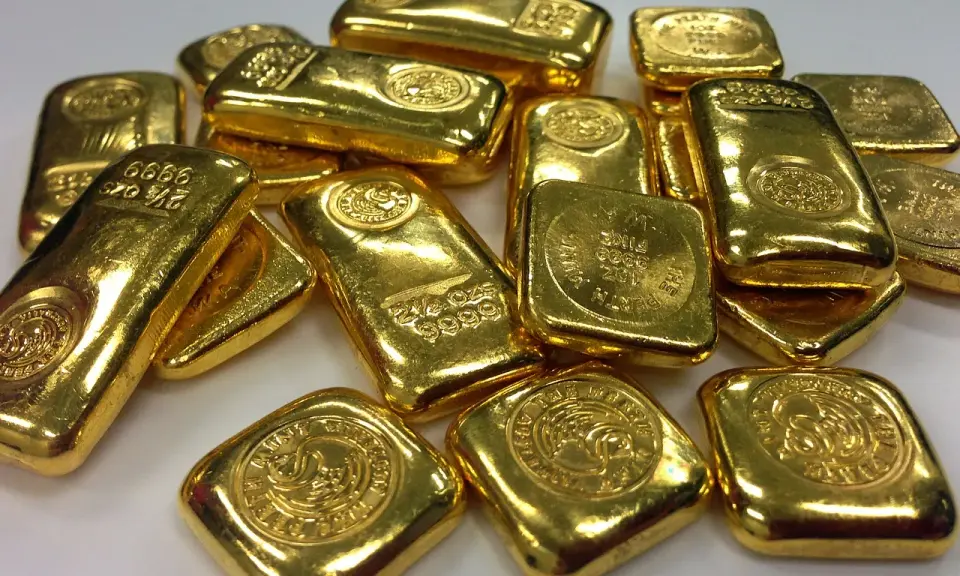 Lingotti d'oro luccicanti, alcuni con incisioni che indicano il peso e la purezza. La domanda "oro 850 quanti carati" è un'ottima domanda per valutare il valore di questi preziosi lingotti.
