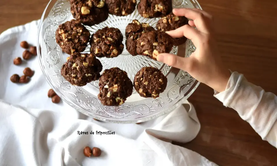 Délicieux cookies au chocolat et noisettes, parfaits pour savoir que faire avec un reste de ganache au chocolat. Une main en prend un.