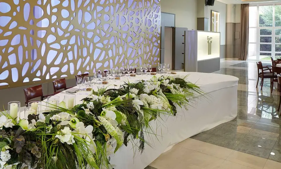 Elegante mesa presidencial boda con arreglos florales blancos y verdes, velas y copas.