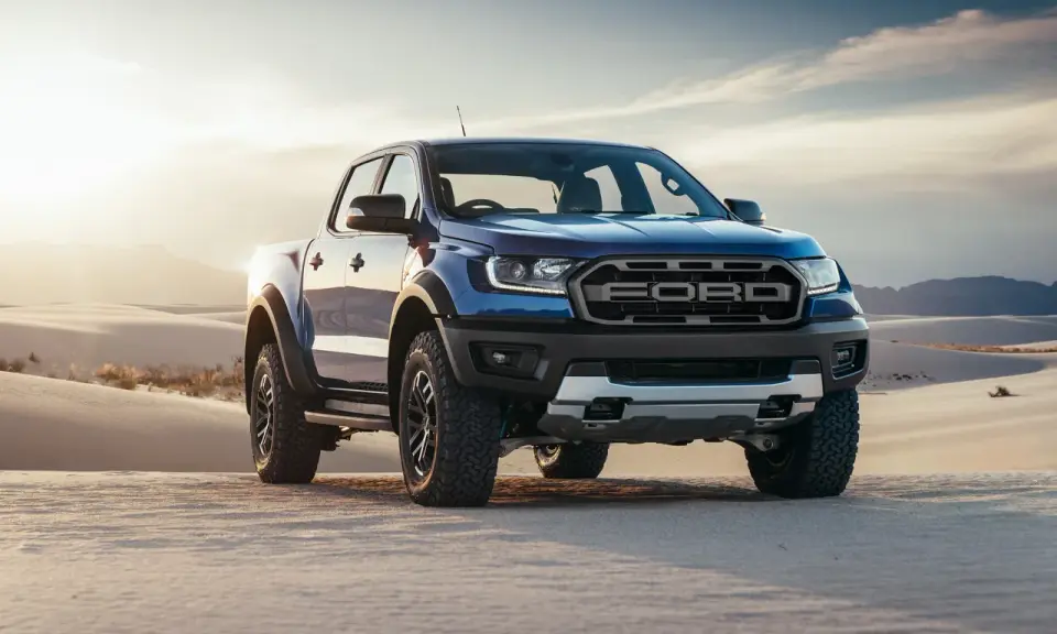 Niebieski Ford Ranger Raptor przemierza piaszczyste wydmy o zachodzie słońca.
