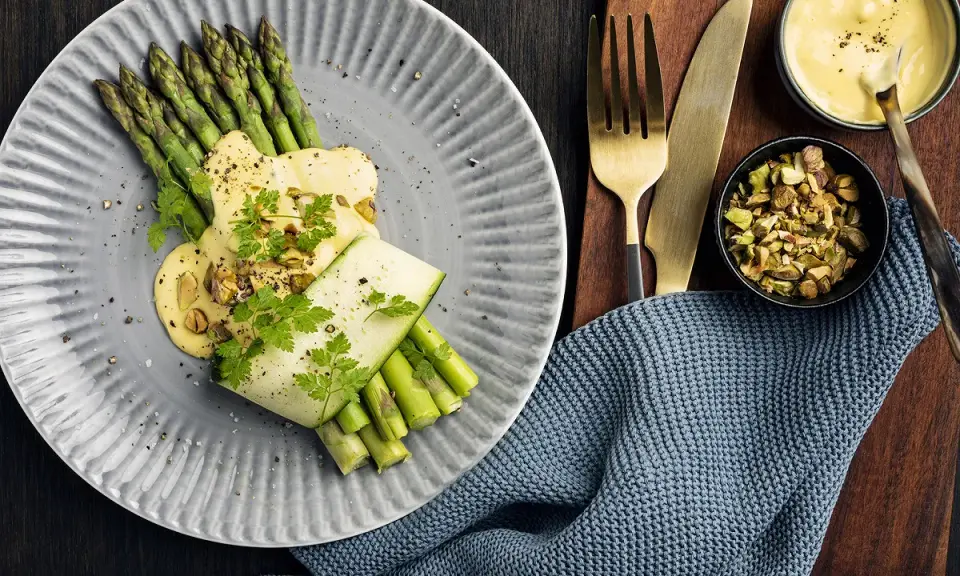 Une belle recette d'asperges vertes, nappées d'une sauce crémeuse et garnies de pistaches concassées. Un délice visuel et gustatif.