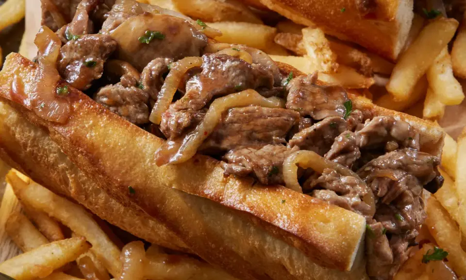 Un delicioso pepito de ternera jugoso, relleno de tiernos trozos de carne y cebolla caramelizada, acompañado de crujientes patatas fritas.