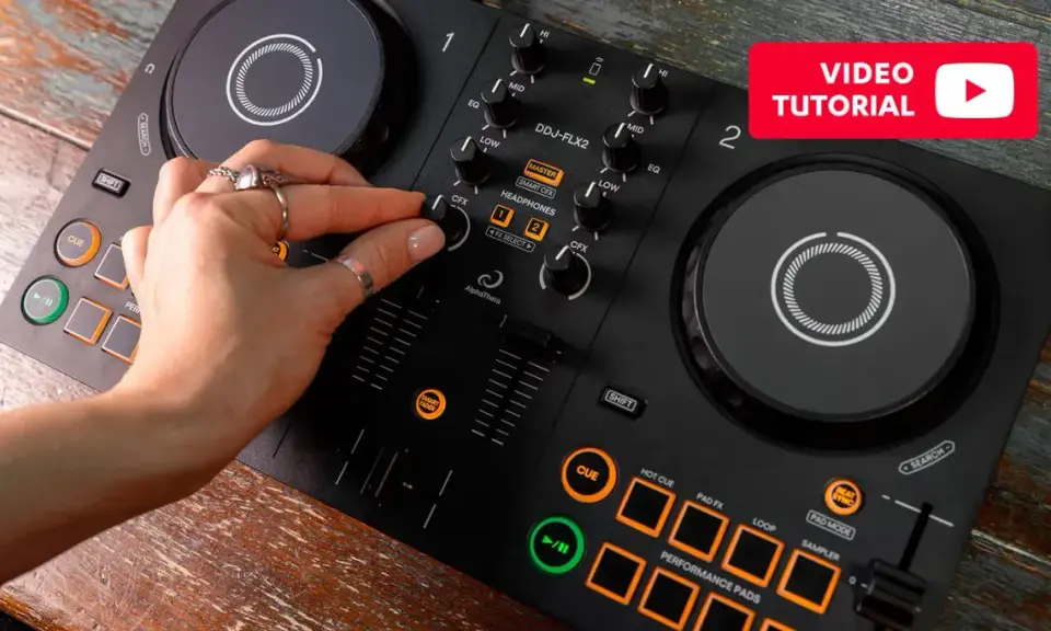 Main d'une personne manipulant une table de mixage pour créer sa propre musique électro. Tutoriel vidéo disponible.