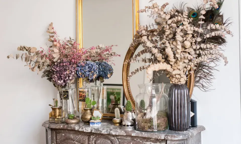 Des idées pour que faire avec des hortensias séchés : bouquets, décorations avec des plumes de paon et des cactus sur une cheminée en marbre.