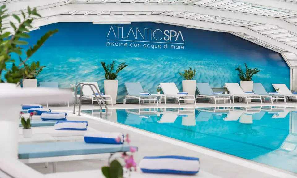 Rilassati nei bagni Riccione con piscina, un'oasi di benessere con lettini e teli blu.