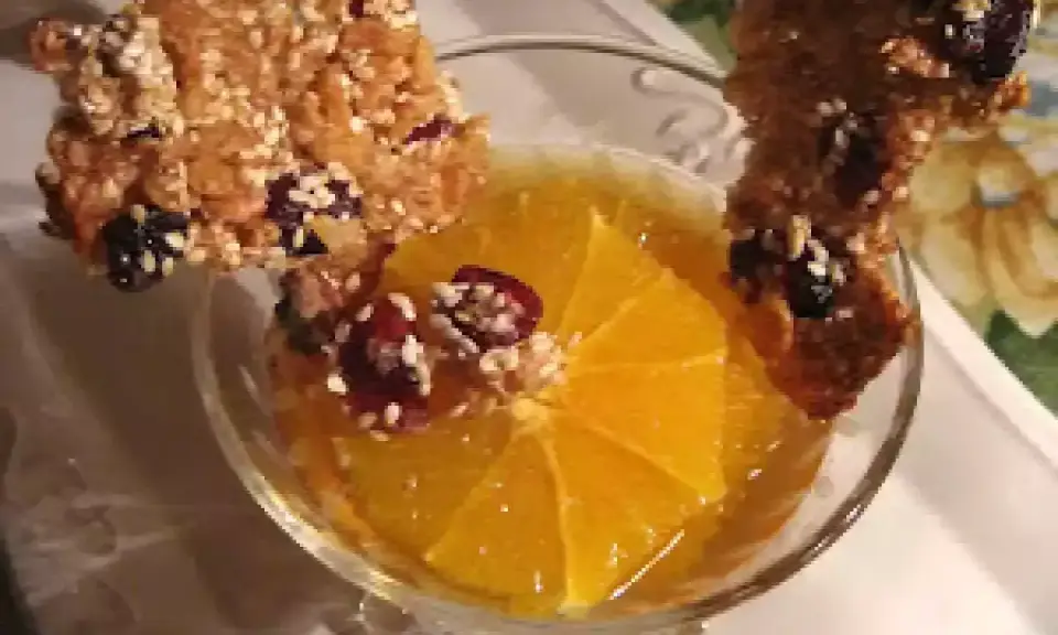 Délicieuse tuile de riz croustillante garnie de fruits secs, posée sur une tranche d'orange dans un verre.