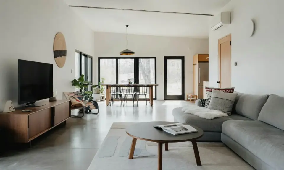 Salón moderno con sofá gris, mesa de centro y comedor. El color gris se combina con tonos madera y blanco, creando un ambiente sereno.