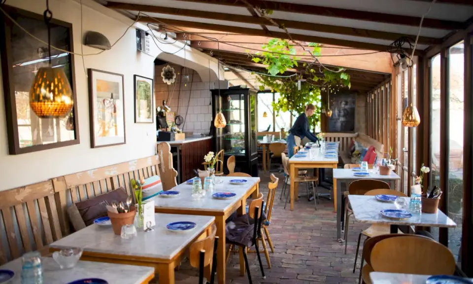 Mysig vinterträdgård med rustika bänkar och marmorbord, en av många annorlunda restauranger i Skåne.
