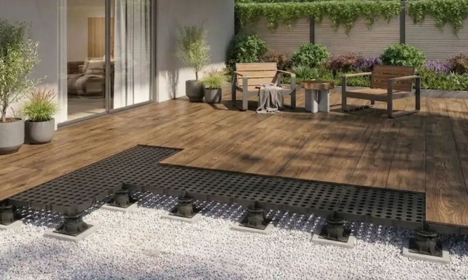 Terrassenplatten mit schwarzem Unterbau auf Kiesbett, bereit für die Montage. Ein moderner Aufbau für eine langlebige Terrasse.