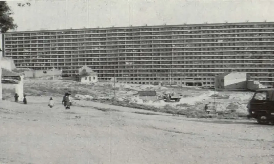 Edificio masivo de apartamentos en construcción, con obreros y vehículos en el sitio. Imagina cómo se veía cuando se inventó el cemento.