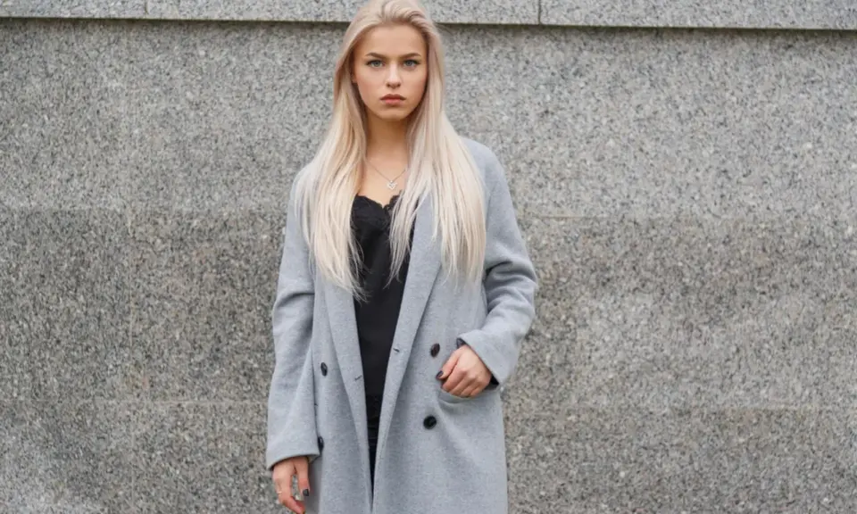 Blondynka w szarym płaszczu i czarnej koronkowej bluzce. Czerń to klasyczny wybór, jaki kolor pasuje do szarego ubrania, dodając elegancji.
