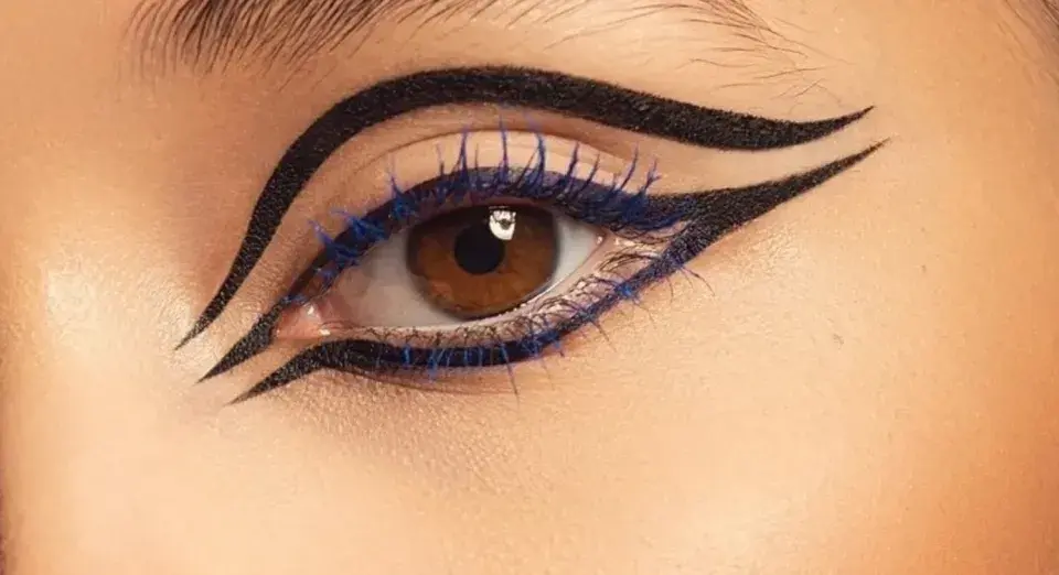 Ojo con delineado dramático y pestañas azules, inspirado en el maquillaje egipcio.