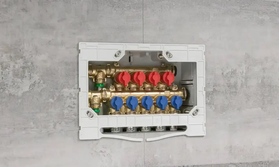 Installazione di collettori idraulici in un box a muro. Questi collettori, con valvole rosse e blu, sono essenziali per la distribuzione dell'acqua.