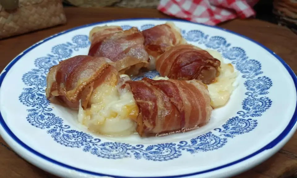 Involtini di interiora pugliesi avvolti in pancetta croccante, serviti su un piatto bianco con decorazioni blu.