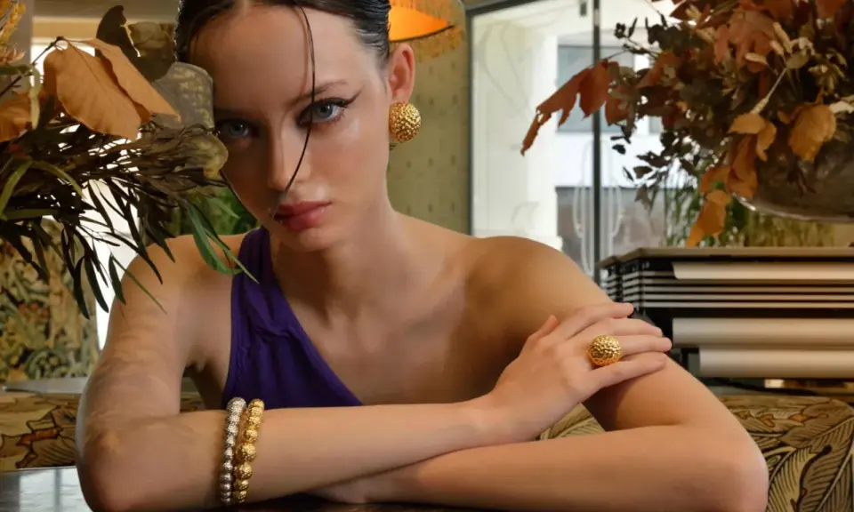 Modella con gioielli dorati, un monile che ricorda come l'oro si rovina con l'acqua di mare, ma qui splende.