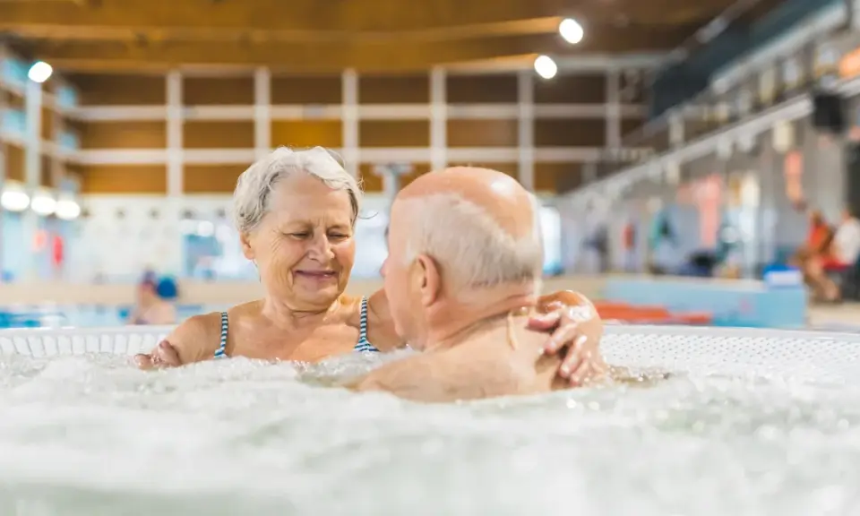 Uśmiechnięta para seniorów relaksuje się w jacuzzi w basenie. To wspaniałe miejsce, jak sanatorium szpitalne, gdzie można odzyskać siły.