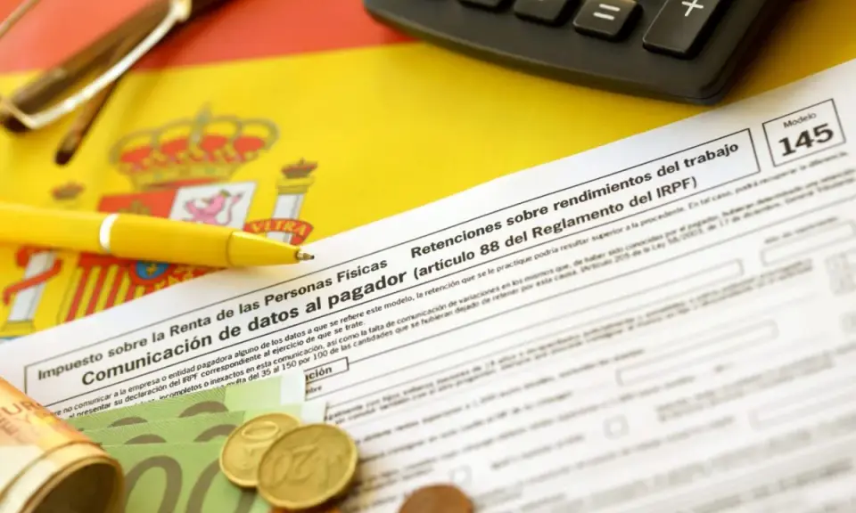 Documentos fiscales españoles, calculadora, bolígrafo amarillo y dinero, listos para cuando se pagan impuestos en España.