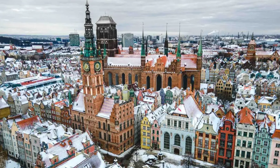 Zimowy widok na Gdańsk. Ratusz Głównego Miasta i Bazylika Mariacka w śniegu. Wspaniałe gdańskie atrakcje turystyczne.
